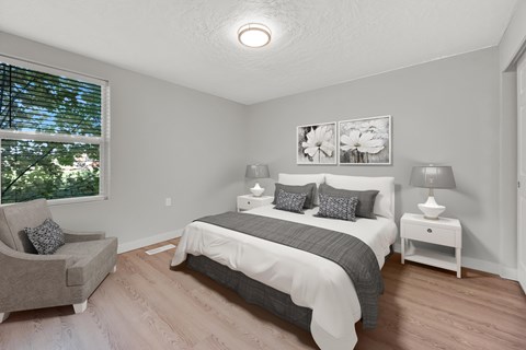 A bedroom with a bed, nightstand, and chair.